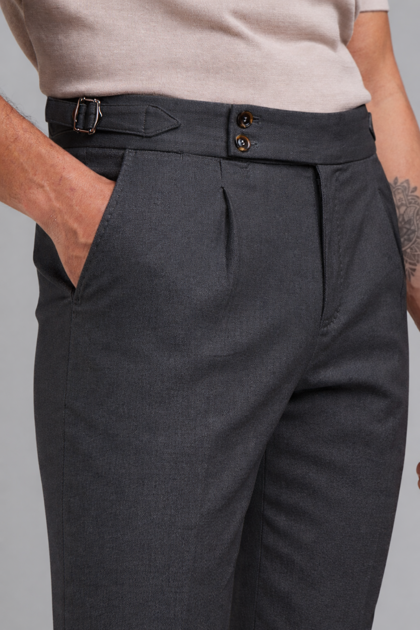 Dark gray pleated pants worn by a person on a plain background