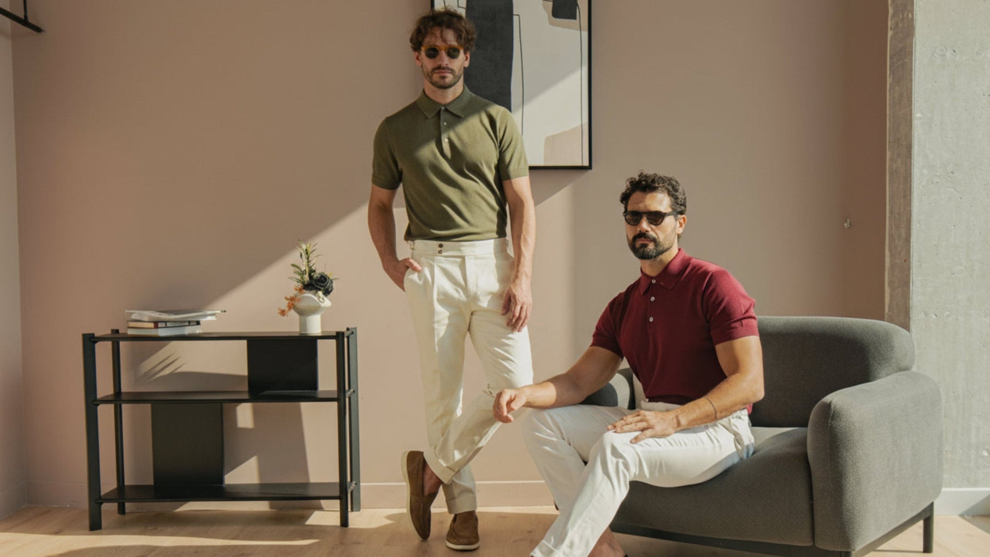 Two men in casual attire sitting and standing in a modern living room.